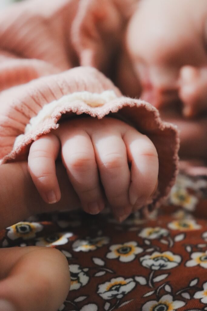 A close-up of a baby's hand holding an adult finger, displaying a tender connection.